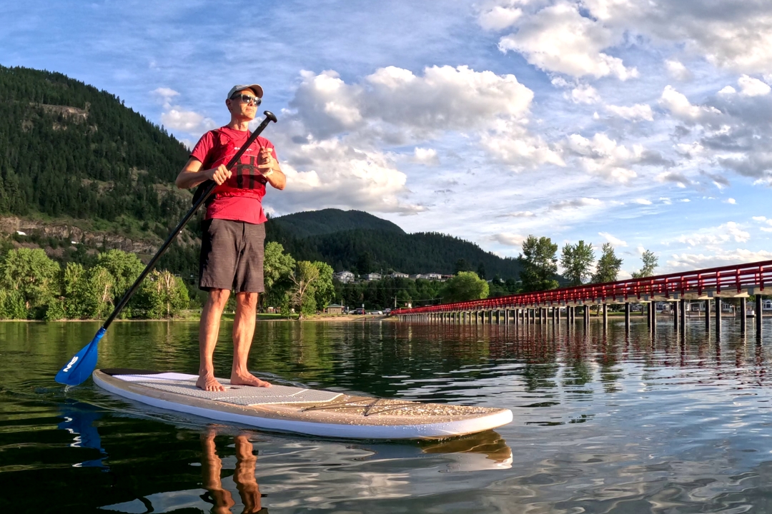 Person paddleboarding on calm Shuswap Lake